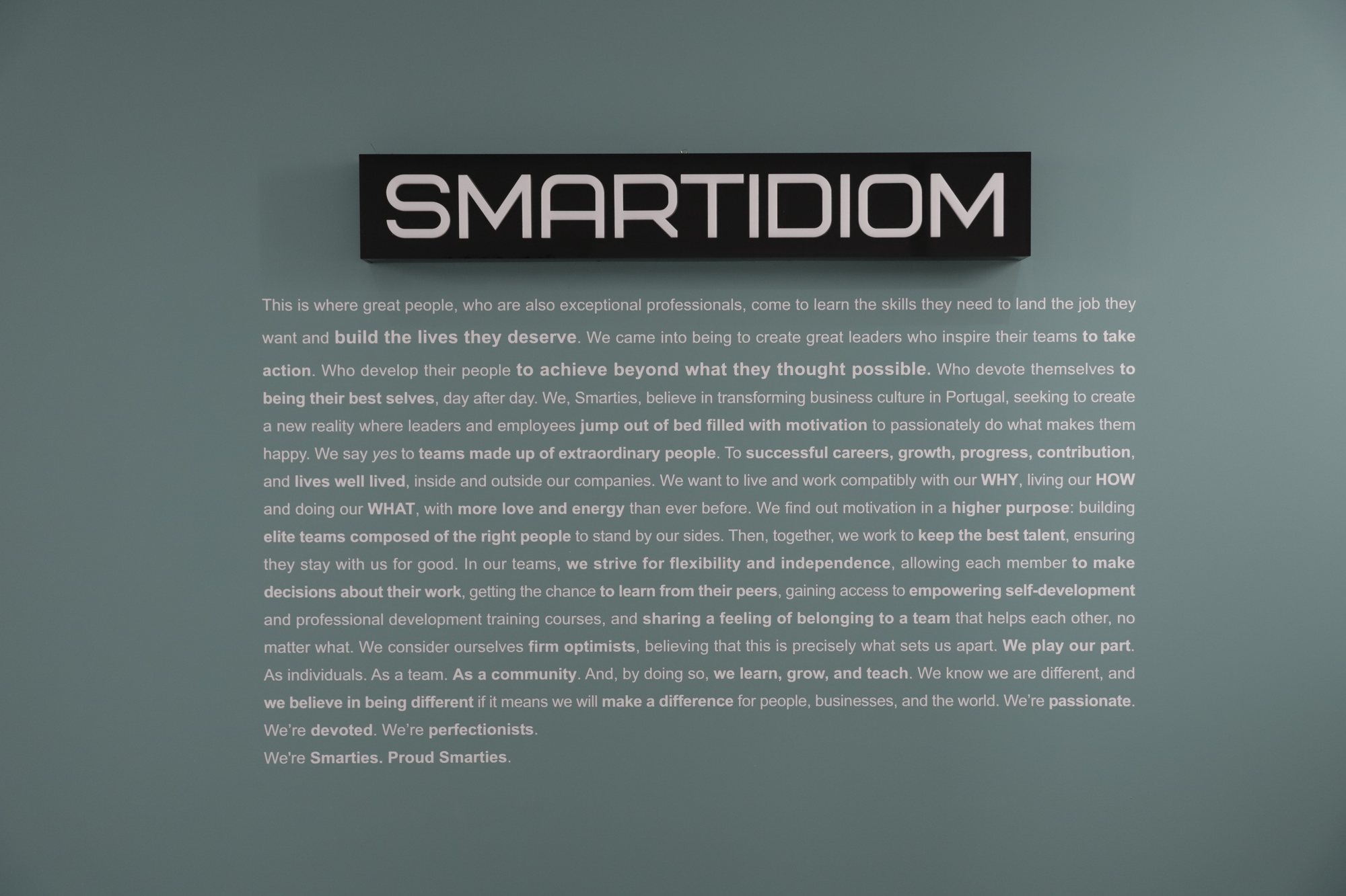 O manifesto da SMARTIDIOM pintado na parede verde do escritório