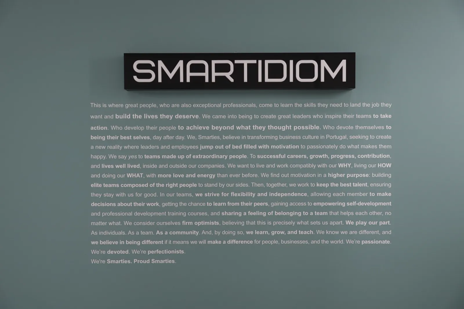 O manifesto da SMARTIDIOM pintado na parede verde do escritório